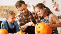 Children and dad making Jack-o-Lantern together at home, carving Halloween pumpkin