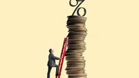 Man Leans Ladder Against Tall Stack Of Coins Topped With Interest Rate Symbol