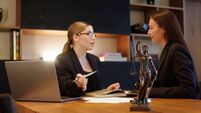 A female lawyer at her workplace communicates with a young client, discussing issues of legal significance. Consultation concept