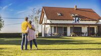 Couple,man and woman,hugging each other while standing on the lawn in the backyard of their new bought house,rear view,modern ho