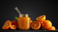 Orange jam in glass jar and fresh fruits on a black background.