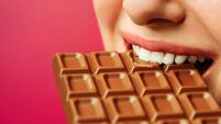 woman eating chocolate. Isolate on pink background
