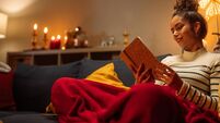 Young woman reading a book on sofa at home during christmas time
