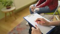 Close up of a female psychologist taking notes and a students knees