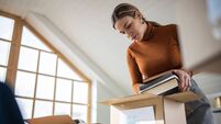 Caring Caucasian young woman packing toys and books for donation into cardboard box