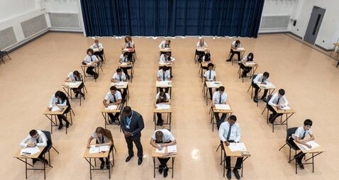 One male teacher checking on rows of teenage students taking a school exam shot from a high angle perspective, Newcastle upon Ty