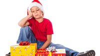 Sad boy with gift box in christmas hat