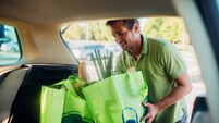 Man packing full shopping bags into the car trunk