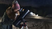 Teenage girl observing the winter night sky with telescope