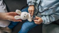 Little doctor using stethoscope on teddy bear at home