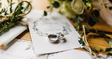 Stylish rings, flowers on wooden table background. Letters from the bride and groom. Vows. Engagement. Luxury marriage and weddi