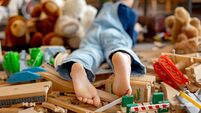 Child, cute boy, playing with toys in a playroom, focus on his feet