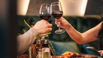 Close up shot of man and woman toasting and drinking red wine from glasses on dinner