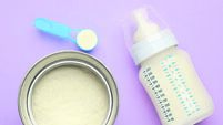 Feeding bottle with infant formula and powder on violet  background, flat lay