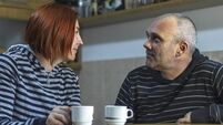 Portrait in profile of adult couple who are drinking coffee in the kitchen looking into each other's eyes.