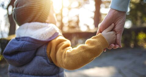 Close up of mother and a child hands at the sunset.