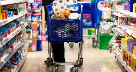 Full shopping cart, customer is stocking vital needs because of global chaos. Shopping with blur supermarket store products, int