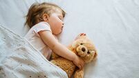 Little baby sleeping on bed embracing soft toy, free space