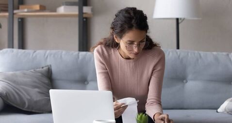 Serious female holds paper invoice calculate expenses makes report