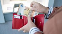 Unrecognizable female holding in hands wallet with euro money near the ATM. Withdrawing cash to pay for services, a loan or stud